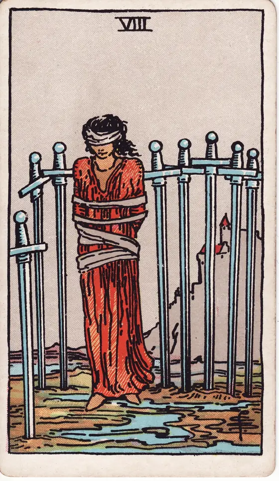 Eight of Swords tarot card from the Rider-Waite-Smith deck: a bound and blindfolded woman standing among eight swords set in the ground.