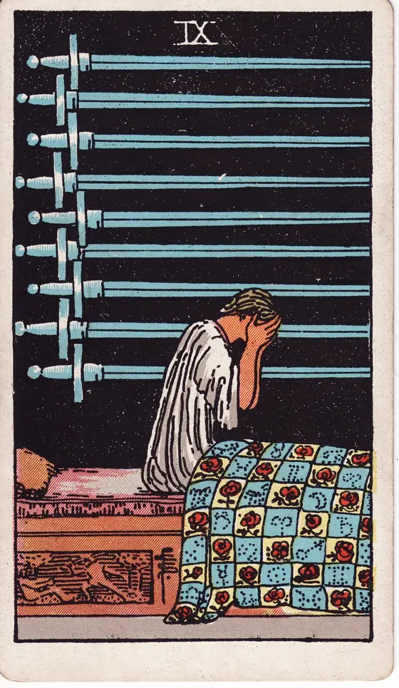 Nine of Swords tarot card from the Rider-Waite-Smith deck: a figure sitting up in bed with face in hands, nine swords on the wall behind.