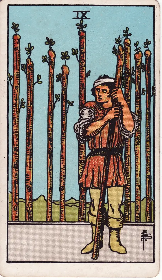 Nine of Wands tarot card from the Rider-Waite-Smith deck: a bandaged man leaning on his staff, eight more standing behind him like a fence.