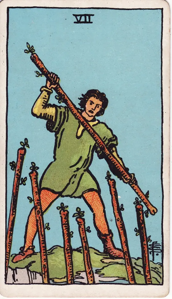 Seven of Wands tarot card from the Rider-Waite-Smith deck: a man on high ground defending his position against six staves rising from below.