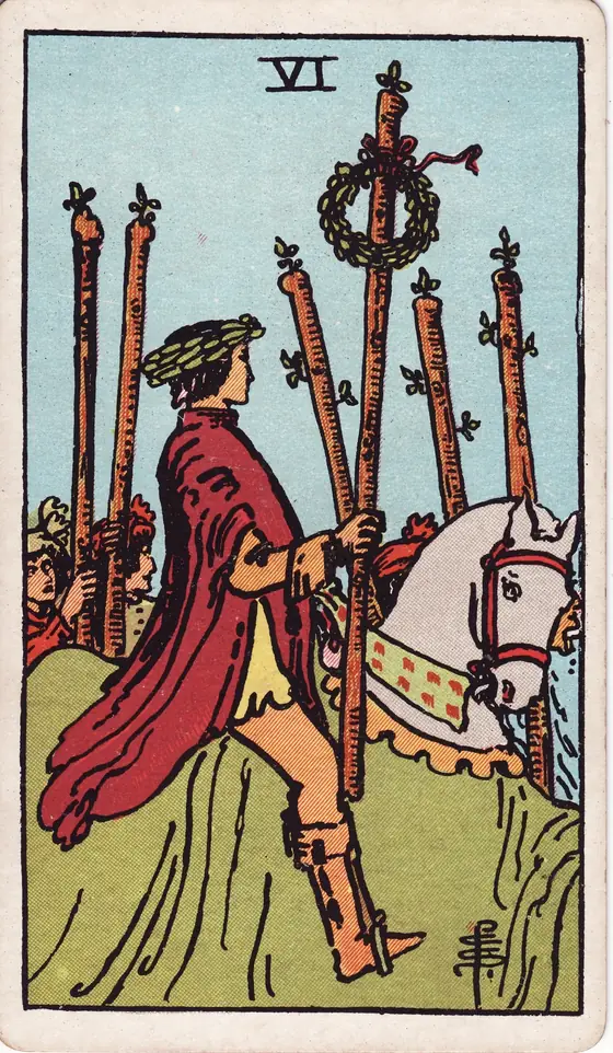 Six of Wands tarot card from the Rider-Waite-Smith deck: a laurel-crowned rider on a white horse carrying a wreathed staff, walkers marching alongside.