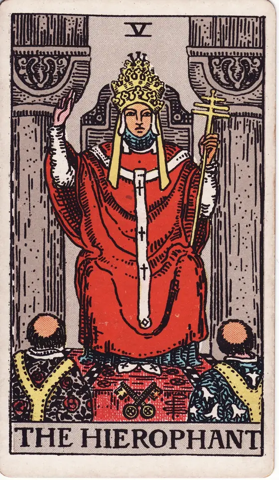 The Hierophant tarot card from the Rider-Waite-Smith deck: a robed priest raising a blessing between two pillars while two acolytes kneel below.