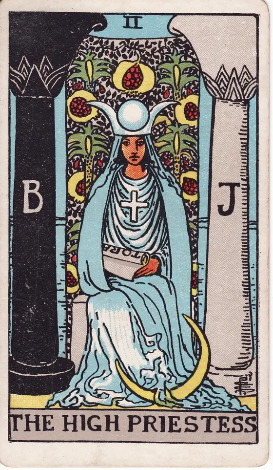 The High Priestess tarot card from the Rider-Waite-Smith deck: a veiled woman seated between a black and a white pillar with a crescent moon at her feet.