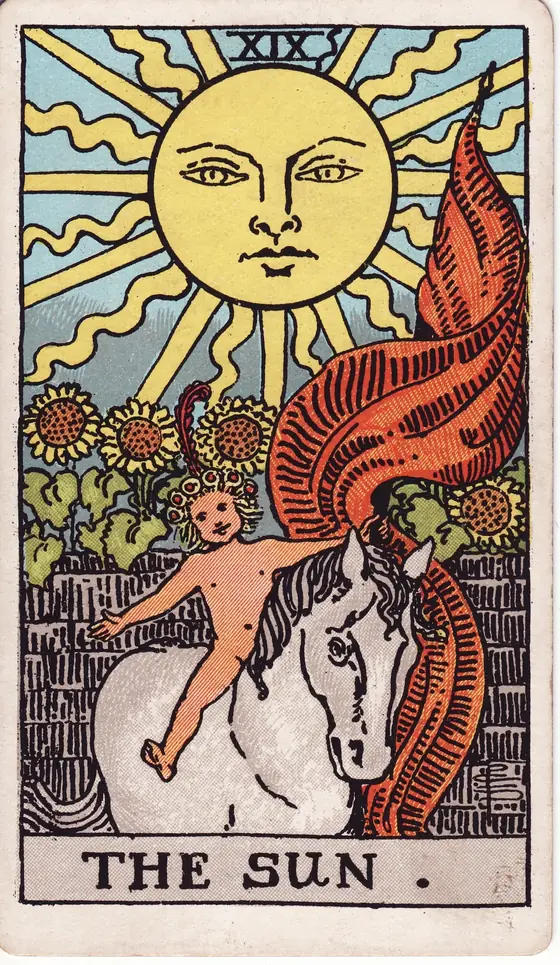 The Sun tarot card from the Rider-Waite-Smith deck: a child on a white horse beneath a beaming sun, sunflowers rising over a garden wall.
