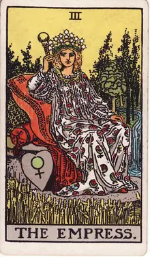 The Empress tarot card from the Rider-Waite-Smith deck: a crowned woman reclining on cushions in a field of ripe wheat, a shield bearing the sign of Venus beside her.