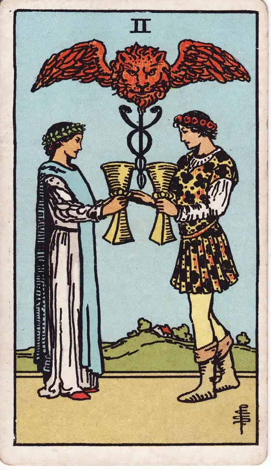 Two of Cups tarot card from the Rider-Waite-Smith deck: a man and a woman exchanging cups beneath a winged lion's head and a caduceus.
