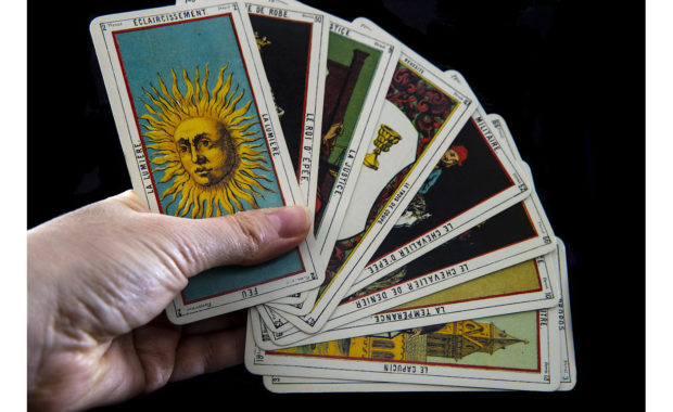 hand holding tarot cards in a fan spread with ton card showing a sun