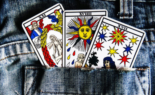 3 colorful tarot cards in a jean pocket showing a person, sun, and stars
