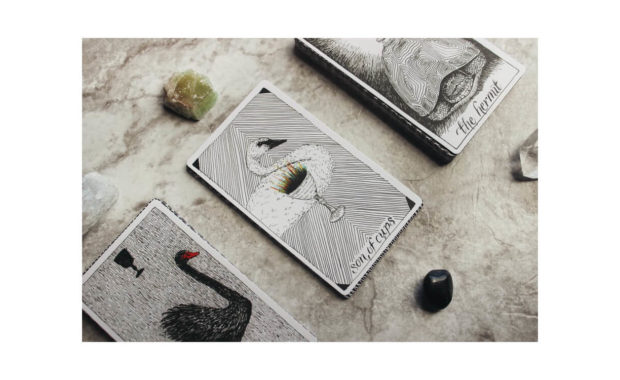 Image showing 3 tarot cards on table with the son of cups and the hermit card names visible. There are two crystals above and below the middle card also