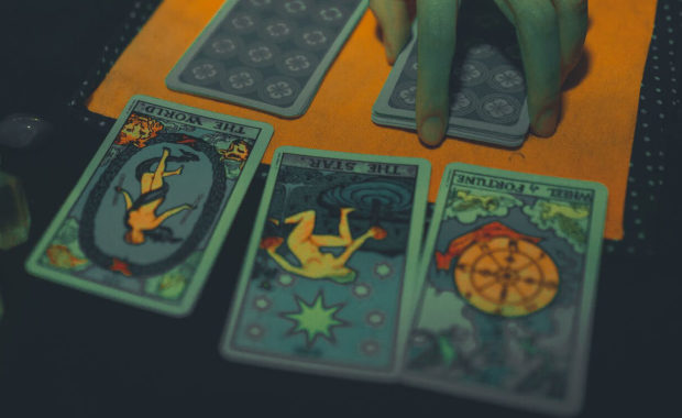 picture showing 3 tarot cards on table with hand placed on card stack