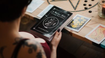 Woman reading the Witch Bible with Tarot Cards